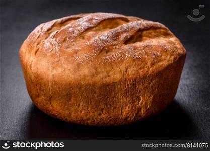 Sourdough rustic homemade healthy bread. Traditional bread, home baking. Tasty fresh baked in oven white bread on a dark concrete background