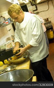 Sous chef prepping food in a busy kitchen.