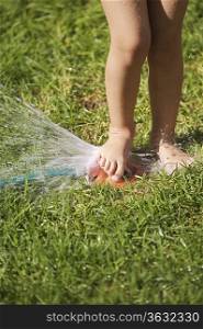 South Africa, Cape Town, girl playing with lawn sprinkler