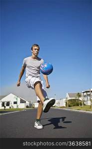 South Africa, Cape Town, teenage boy kicking ball on street