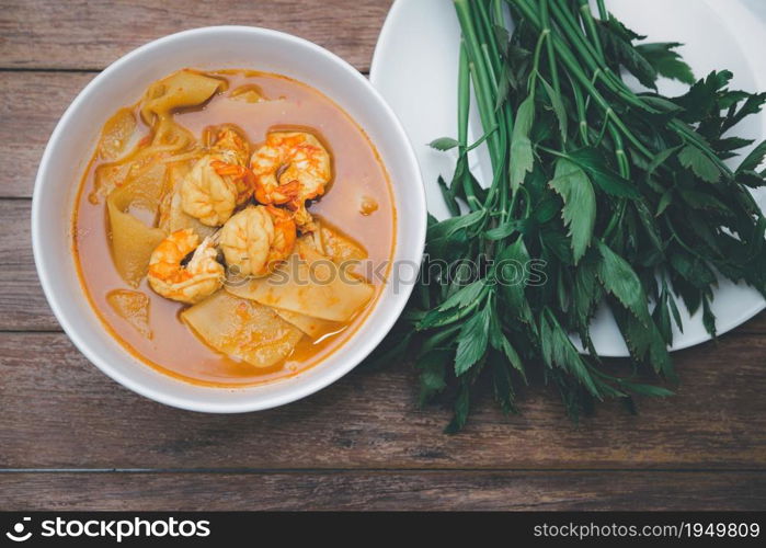 Southern Thai Spicy Sour Yellow Curry with shrimps or prawns and preserved bamboo shoot (Gaaeng Leuuang) eaten with vegetables Water Dropworts or Oenanthe for sale at Thai restaurant. Southern Spicy Yellow Thai Curry (Gaaeng Leuuang)