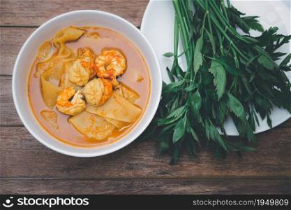 Southern Thai Spicy Sour Yellow Curry with shrimps or prawns and preserved bamboo shoot (Gaaeng Leuuang) eaten with vegetables Water Dropworts or Oenanthe for sale at Thai restaurant. Southern Spicy Yellow Thai Curry (Gaaeng Leuuang)