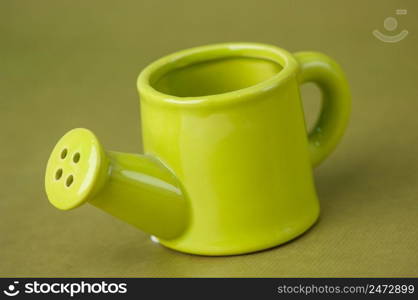 souvenir toy ceramic watering-can on a green background close up. souvenir toy watering can