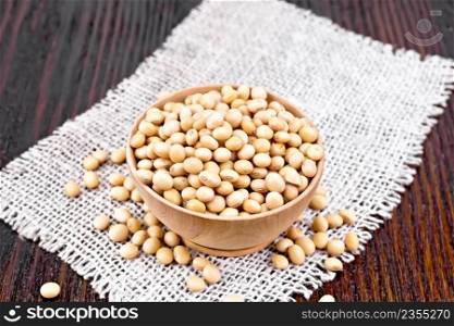 Soy beans in a bowl on burlap on a wooden board background