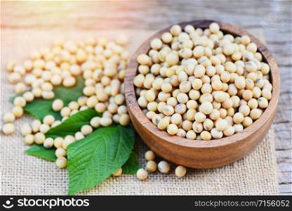 Soya , Soybean in a wooden bowl agricultural products on the sack background / dry soy beans and green leaf , selective focus