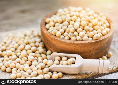 Soybean in a wooden bowl agricultural products on the sack background / dry soy beans