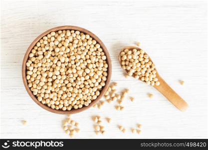 Soybeans in a wooden cup on the old wood table,top view on withe background