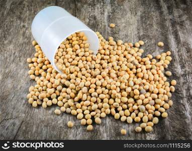 soybeans or soya beans grain seed with cup on rustic wood background