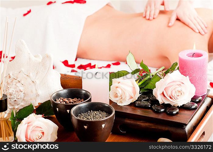 Spa - accessories in foreground, woman enjoying a back massage in the background