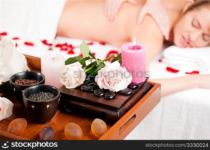 Spa - accessories in foreground, woman enjoying a back massage in the background