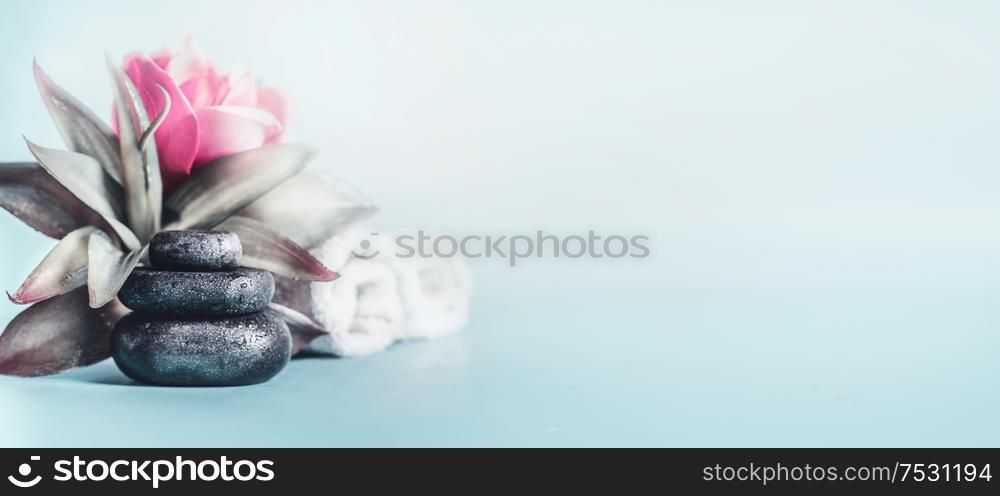 Spa and wellness concept with stack of zen stones, flowers and towels at light blue background with copy space. Relax and calm treatment. Still life. Banner
