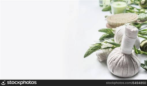 Spa background with massage herbal balls , green herbs and flowers on white. Beauty, healthy body care and wellness concept