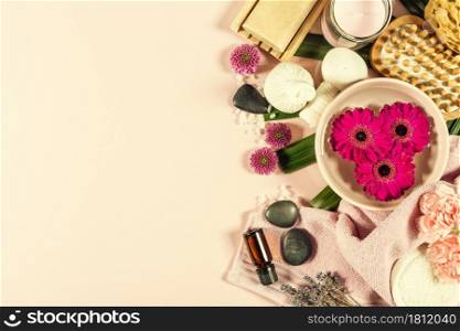 Spa background with sea salt, bowl ,flowers, water, soap bar, candles, essential oils, massage brush and flowers,top view. Flat lay. Pink background. Spa background, relaxation concept on pink background. Flat lay