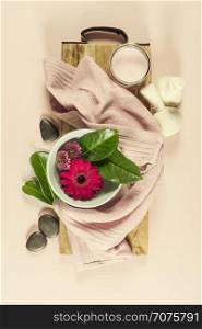 Spa background with sea salt, bowl ,flowers, water, soap bar, candles, essential oils, massage brush and flowers,top view. Flat lay. Pink background
