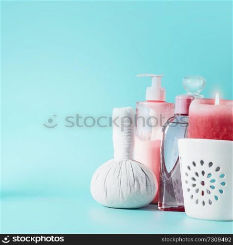 Spa beauty background with tools: cream, burning candles, massage herbal stamp standing on pastel blue table. Salon wellness therapy treatments and equipment. Body care and beauty concept.