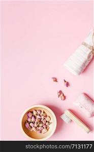 Spa, beauty cosmetics and body care treatment concept with copy space. Creative top view flat lay composition with bath accessories, organic DIY rose soap and dry flowers in a bowl on pink background
