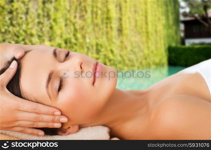spa, beauty, people and body care concept - beautiful woman getting face treatment over green natural background