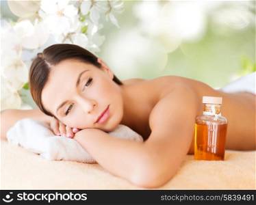 spa, beauty, people and body care concept - happy woman lying on the massage desk over green natural background