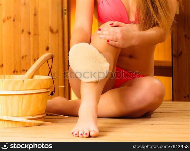 Spa beauty treatment and health concept. Young woman with exfoliation glove pink bikini resting in wood sauna, indoor