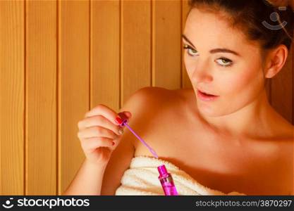 Spa beauty treatment and relaxation concept. Woman relaxing in wooden sauna room having fun blowing soap bubbles