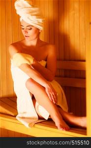 Spa beauty treatment and relaxation concept. Woman white towel relaxing in wooden sauna room, making massage with exfoliation glove