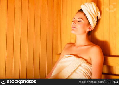 Spa beauty treatment and relaxation concept. Woman white towel relaxing in wooden sauna room.