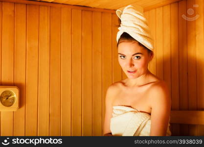 Spa beauty treatment and relaxation concept. Woman white towel relaxing in wooden sauna room.