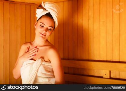 Spa beauty treatment and relaxation concept. Woman white towel relaxing in wooden sauna room.