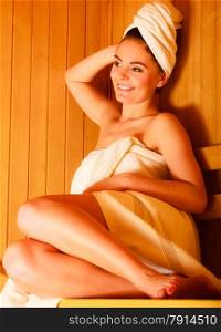 Spa beauty treatment and relaxation concept. Woman white towel relaxing in wooden sauna room.