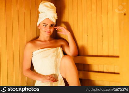 Spa beauty well being and relax concept. Woman in white towel sitting relaxed in wooden sauna