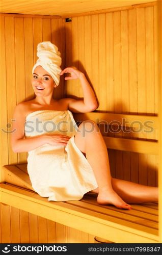 Spa beauty well being and relax concept. Woman in white towel sitting relaxed in wooden sauna