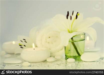 Spa concept (flowers, towel, candle and pebbles). Purple background