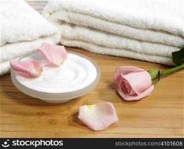 Spa essentials (cream, white towel and pink rose)