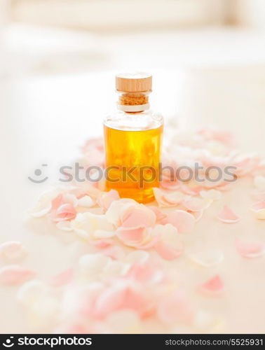 spa, health and beauty concept - closeup of essential oil and rose petals