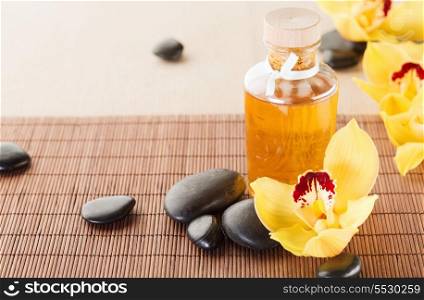 spa, health and beauty concept - closeup of essential oil, massage stones and orchid flowers