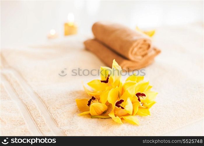 spa, health and beauty concept - closeup of towels, flowers and candles