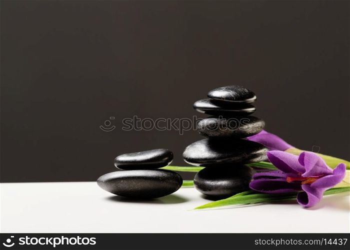 spa, heath and beauty concept - massage stones with flowers on mat