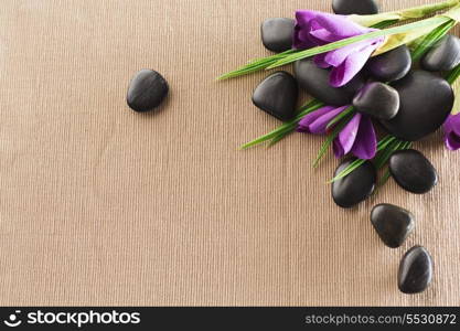 spa, heath and beauty concept - massage stones with flowers on mat