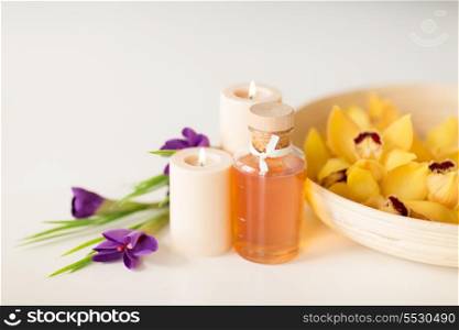 spa, heath and beauty concept -orchid flowers in bowl, oil, candles and iris flowers