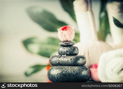 Spa hot stone massage concept with flowers and palm leaves, front view