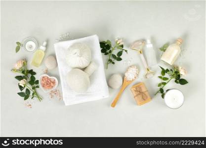 Spa massage Aromatherapy body care background. Spa herbal balls, quartz facial roller, towel, natural cosmetics, bath salt and beautiful roses on gray concrete table. Beauty and health care concept