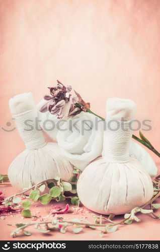 Spa massage setting with herbs and flowers on pink pale background, front view