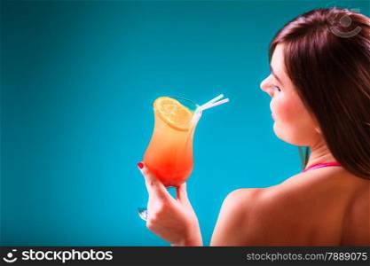 Spa relax and holidays concept. Young woman in swimsuit sideview. Fit female body, girl sitting at poolside holding cocktail glass in hand