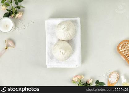 Spa resort therapy background with massage herbal balls , natural SPA accessories and flowers on light grey background. Beauty, healthy body care and wellness concept