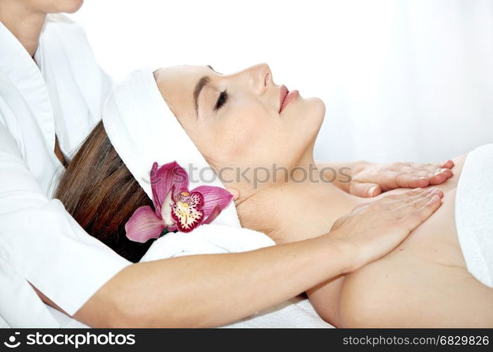 Spa salon: Beautiful Young Woman having Facial Treatment in Spa salon with Orchid in her Long Hair.