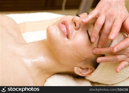 Spa salon: Beautiful Young Woman having Facial Treatment in Spa salon with Massage Oil