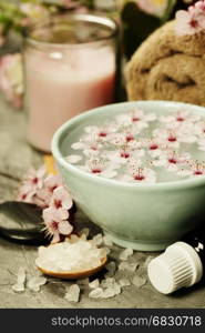 Spa setting. Sea salt, candles, floating flowers, towels on rustic background