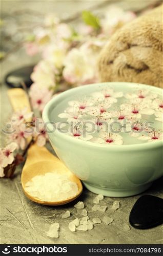 Spa setting. Sea salt, candles, floating flowers, towels on rustic background