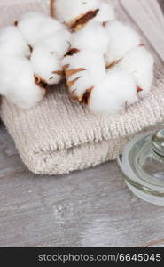 spa setting with cotton buds and towels on gray wooden table. cotton spa