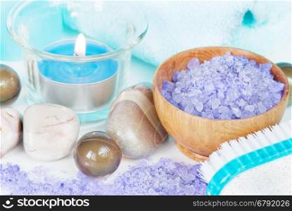 Spa setting with lilac bath salts and a burning candle